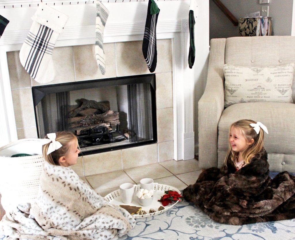 Girls by the fireplace with hot chocolate mugs