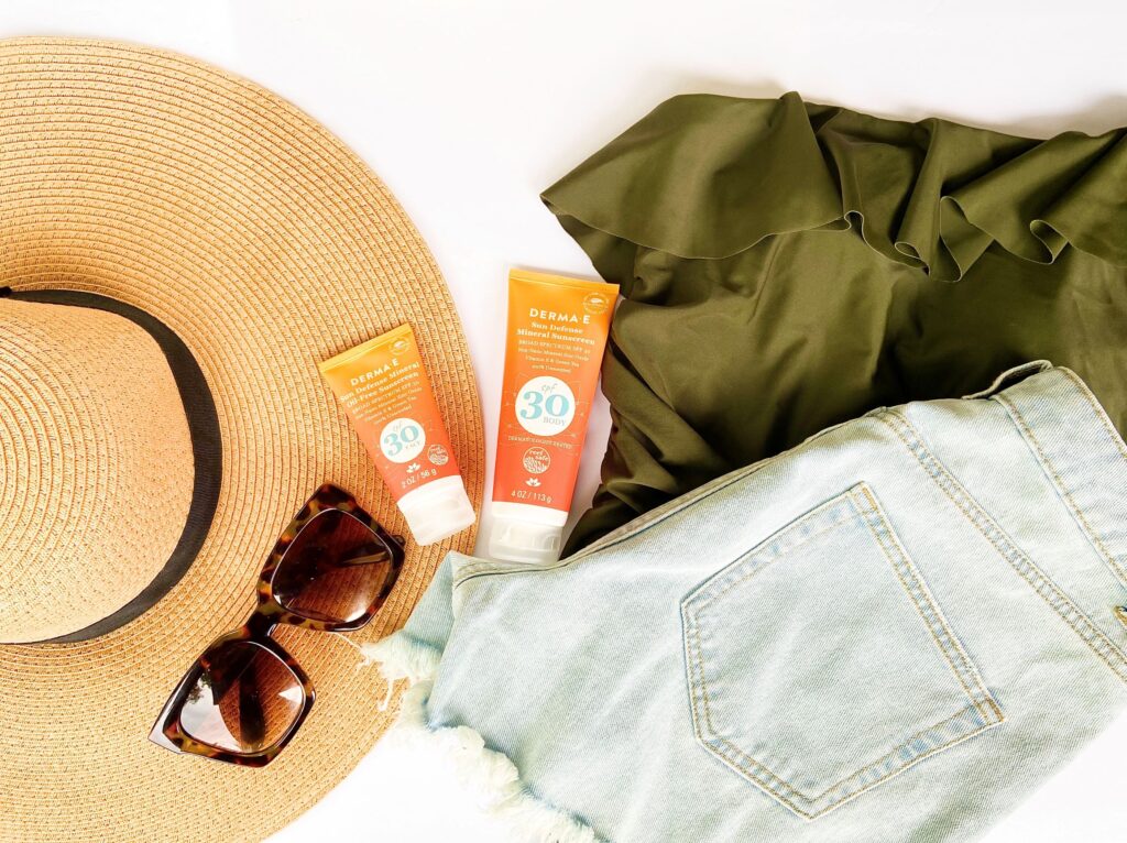 Summer flat lay with clothes, sunglasses, hat, and sunscreen